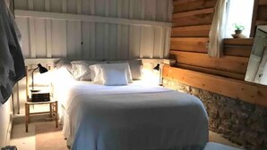 Ein gemütliches Schlafzimmer mit einem großen Bett, Nachttischen und einem Fenster mit Vorhängen.