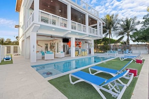 Une maison à deux étages avec une piscine, un espace extérieur aménagé et un coin bar.
