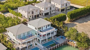 A multi-story residential building with a pool, dock, and outdoor seating areas. - Luxury Waterfront Oasis w Heated Pool and 50' Dock (Marathon)