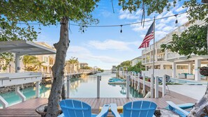 A waterfront deck with blue chairs, a pool, and a view of the water. - Luxury Waterfront Oasis w Heated Pool and 50' Dock (Marathon)
