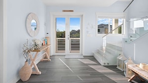 A modern hotel lobby with a wooden floor, a large mirror, a reception desk, and a staircase with glass railings. - Luxury Waterfront Oasis w Heated Pool and 50' Dock (Marathon)