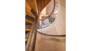 Un escalier en colimaçon avec une rampe en métal et des marches en bois.