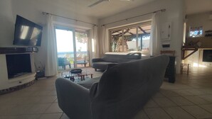 A living room with a television, sofa, and a dining area with a table and chairs. - Costa dei monaci Villas - Tropea (PARGHELIA)