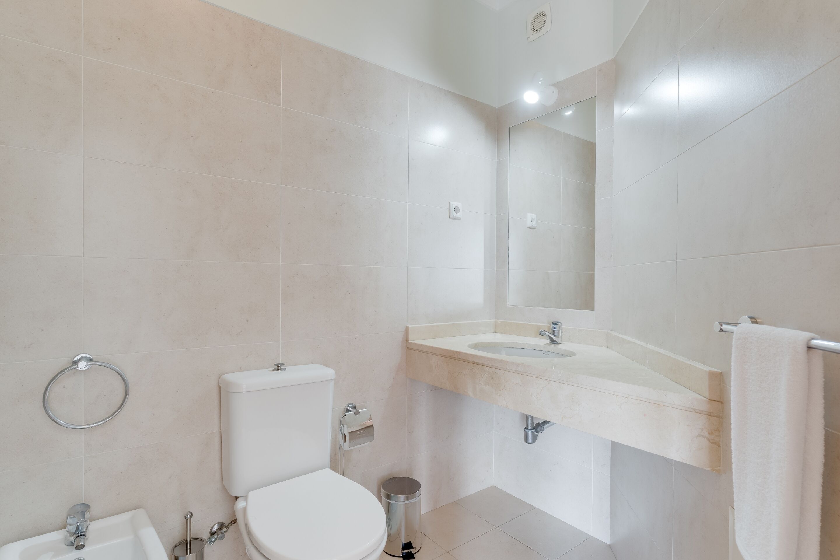 A modern bathroom with a toilet, sink, and mirror.