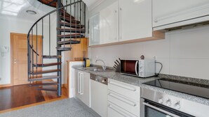 Una cucina moderna con una scala a chiocciola, mobili bianchi, forno integrato e microonde.
