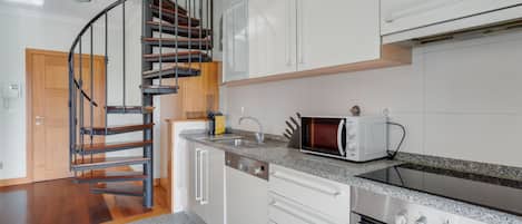 A modern kitchen with a spiral staircase, white cabinetry, a built-in oven, and a microwave.