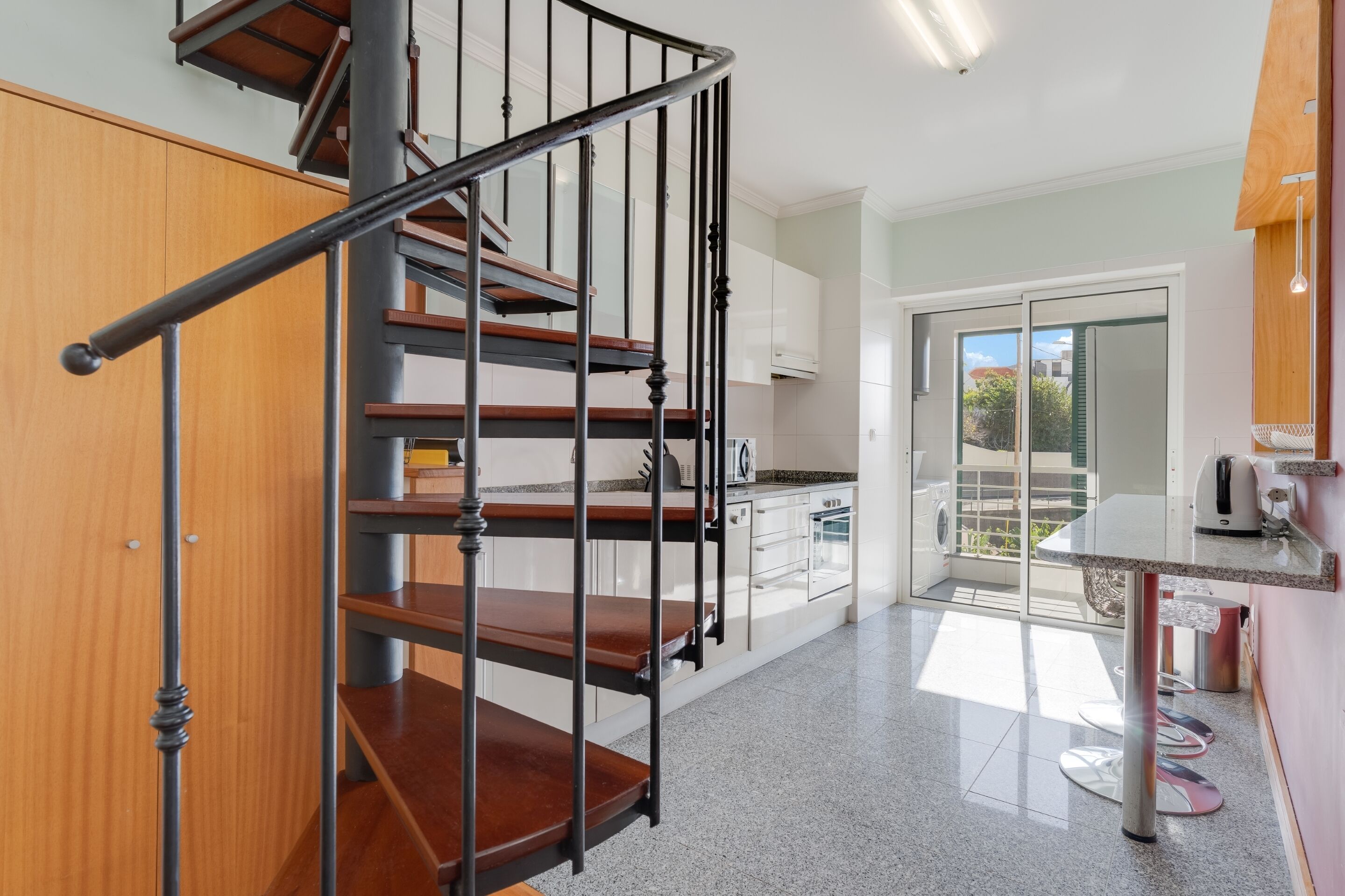 Une cuisine moderne avec un escalier en bois et un coin repas.
