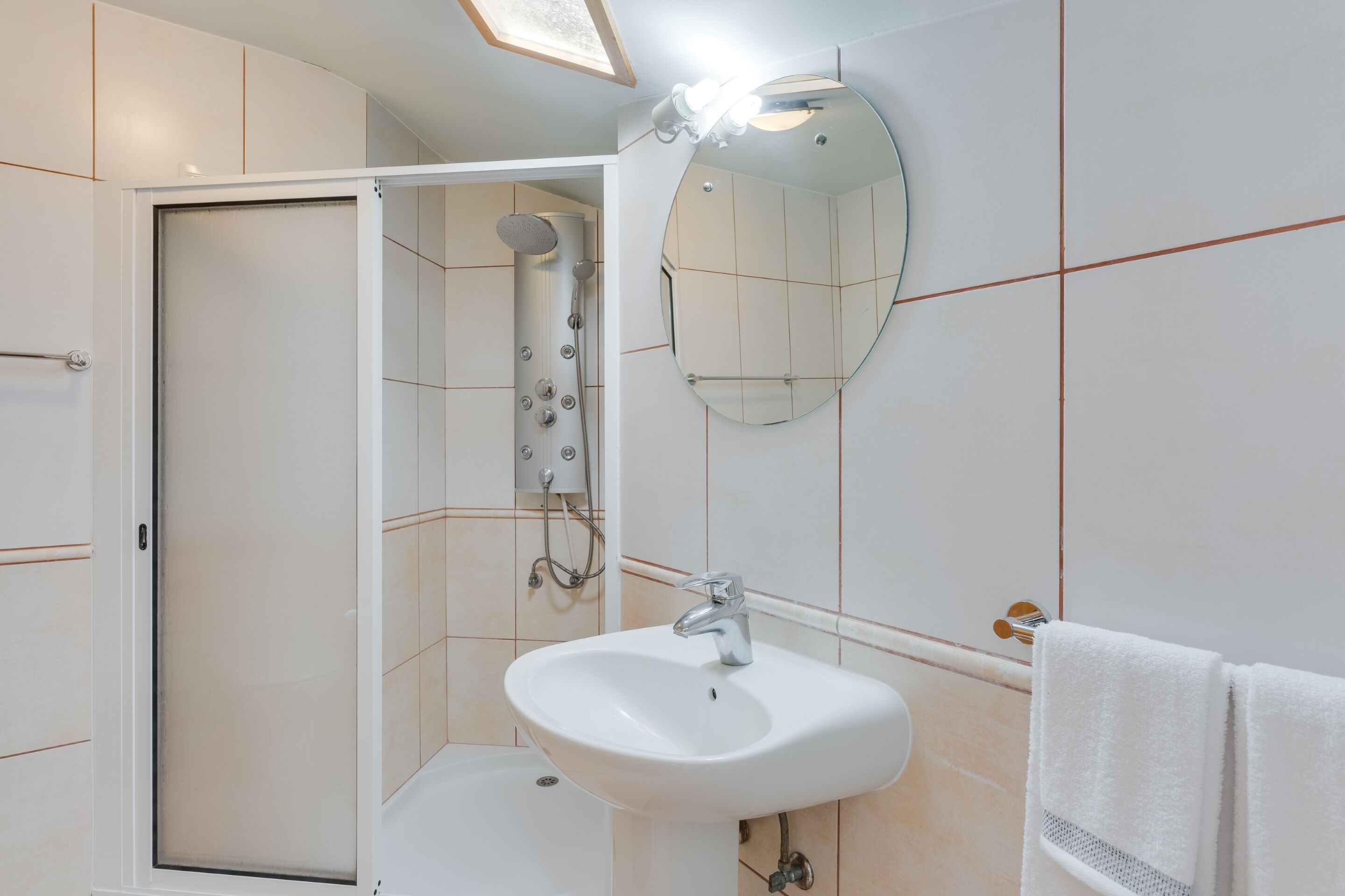 A bathroom with a shower, sink, and mirror.