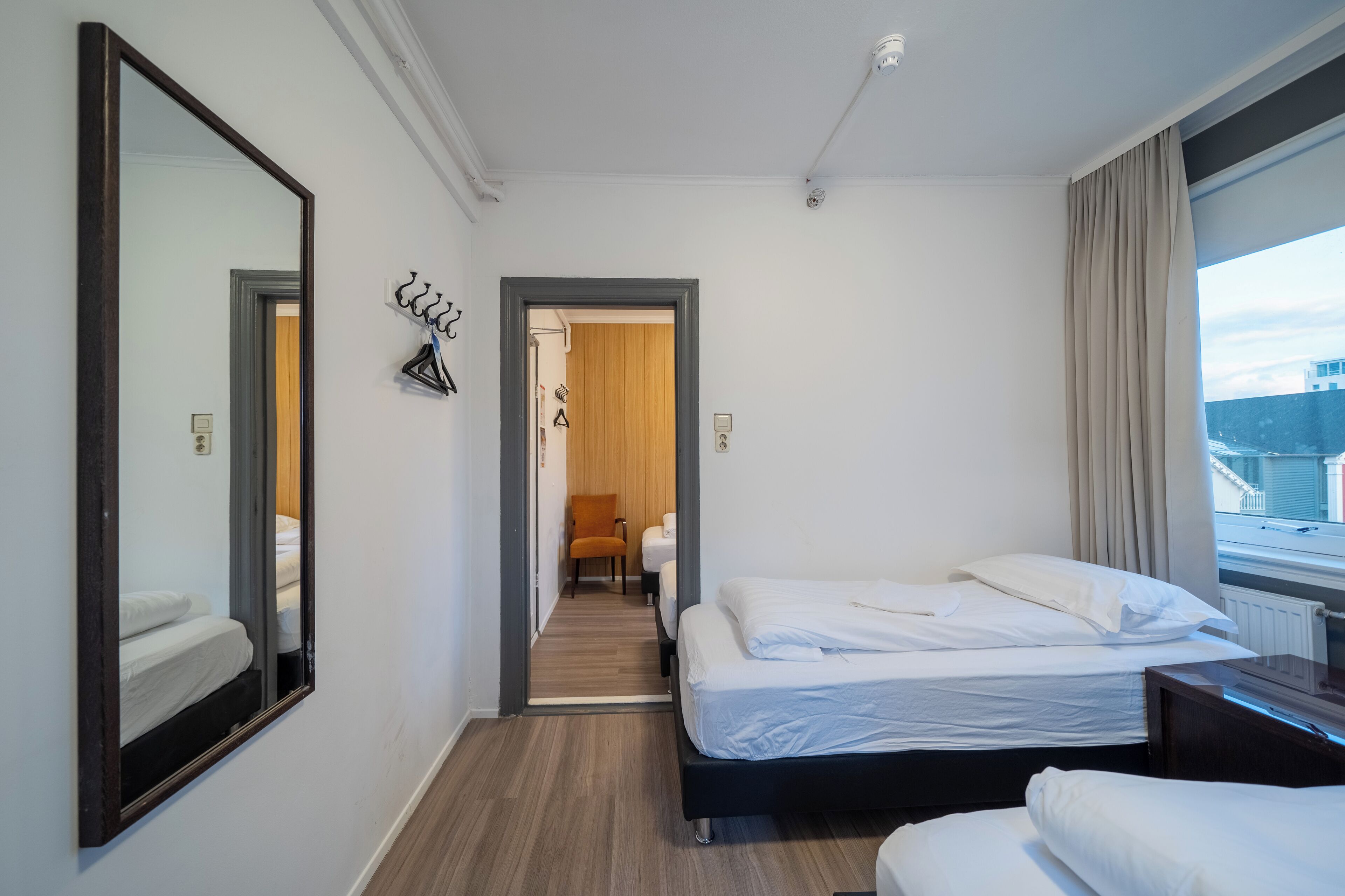 Une chambre d’hôtel avec deux lits, un grand miroir et une vue sur la ville.