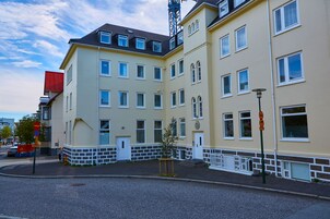 Um edifício de vários andares com fachada bege, detalhes brancos e várias janelas.