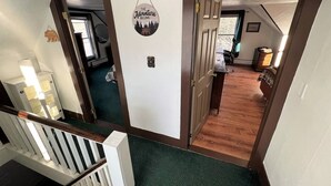A hallway with a wooden door leading to a room with a window, a small rug, and a wall-mounted decoration. - Launch your next adventure from here: plenty of beds, plenty of parking, plenty of fun (Plymouth)