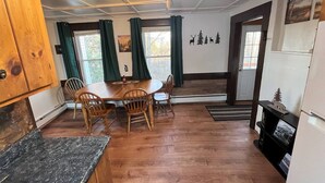 A cozy kitchen with wooden cabinets, a dining table with chairs, and a large window with curtains. - Launch your next adventure from here: plenty of beds, plenty of parking, plenty of fun (Plymouth)
