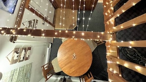 Een meerlaags interieur met een eetgedeelte met een ronde tafel en stoelen, een keuken met een rode aanrecht en een woonruimte met een groot schilderij van een beer.
