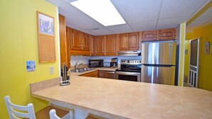 A kitchen with wooden cabinets, a stainless steel refrigerator, a microwave, and a stove.