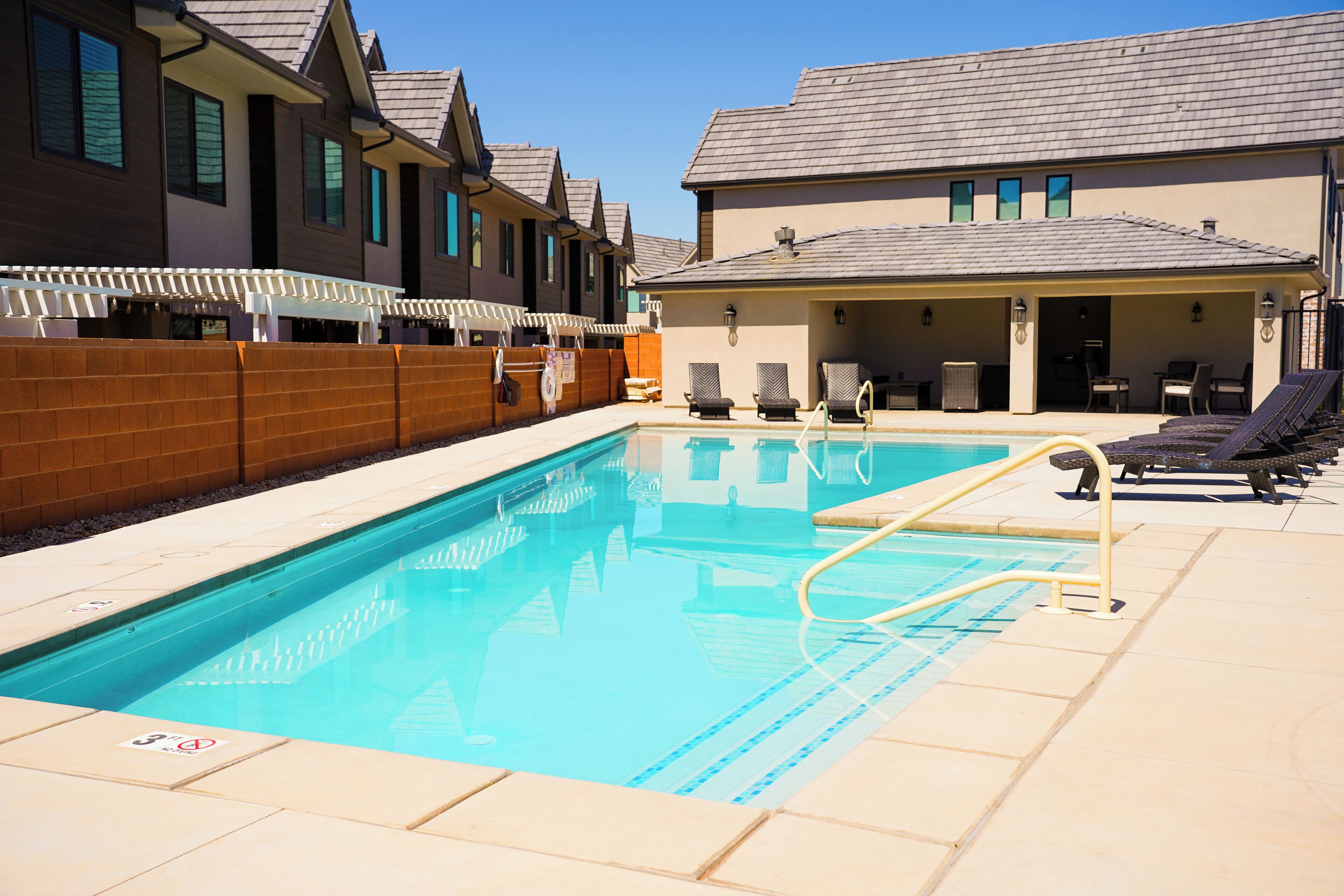 A swimming pool with lounge chairs and a covered seating area.