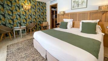 A hotel room with a bed, a desk, a chair, a wardrobe, and a patterned wallpaper.