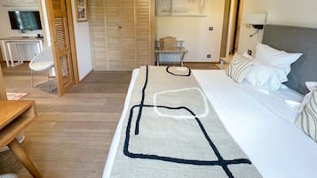 A hotel room with a bed, a desk, a chair, a TV, and a wardrobe.