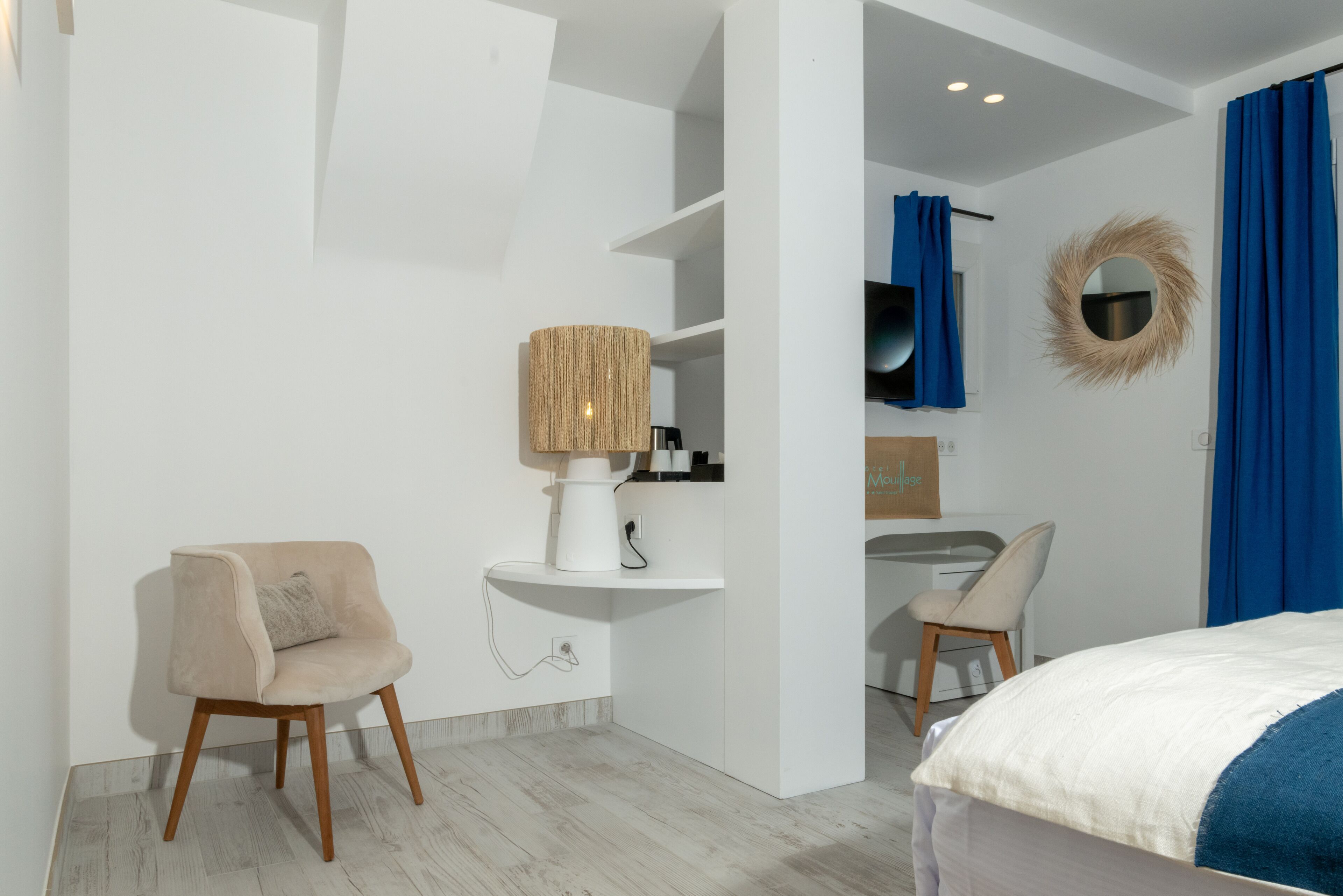 A modern bedroom with a bed, a chair, a desk, and a vanity with a mirror.