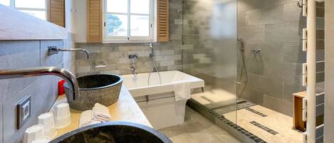 A modern bathroom with a bathtub, shower, and a large basin.