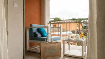 A balcony with a blue chair, a white table with a tray, and a brown bag with text.