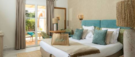 A bedroom with a bed, a large window with curtains, a nightstand, and a lamp.