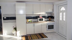 Una cocina compacta con gabinetes blancos, un microondas, una estufa y un lavabo.
