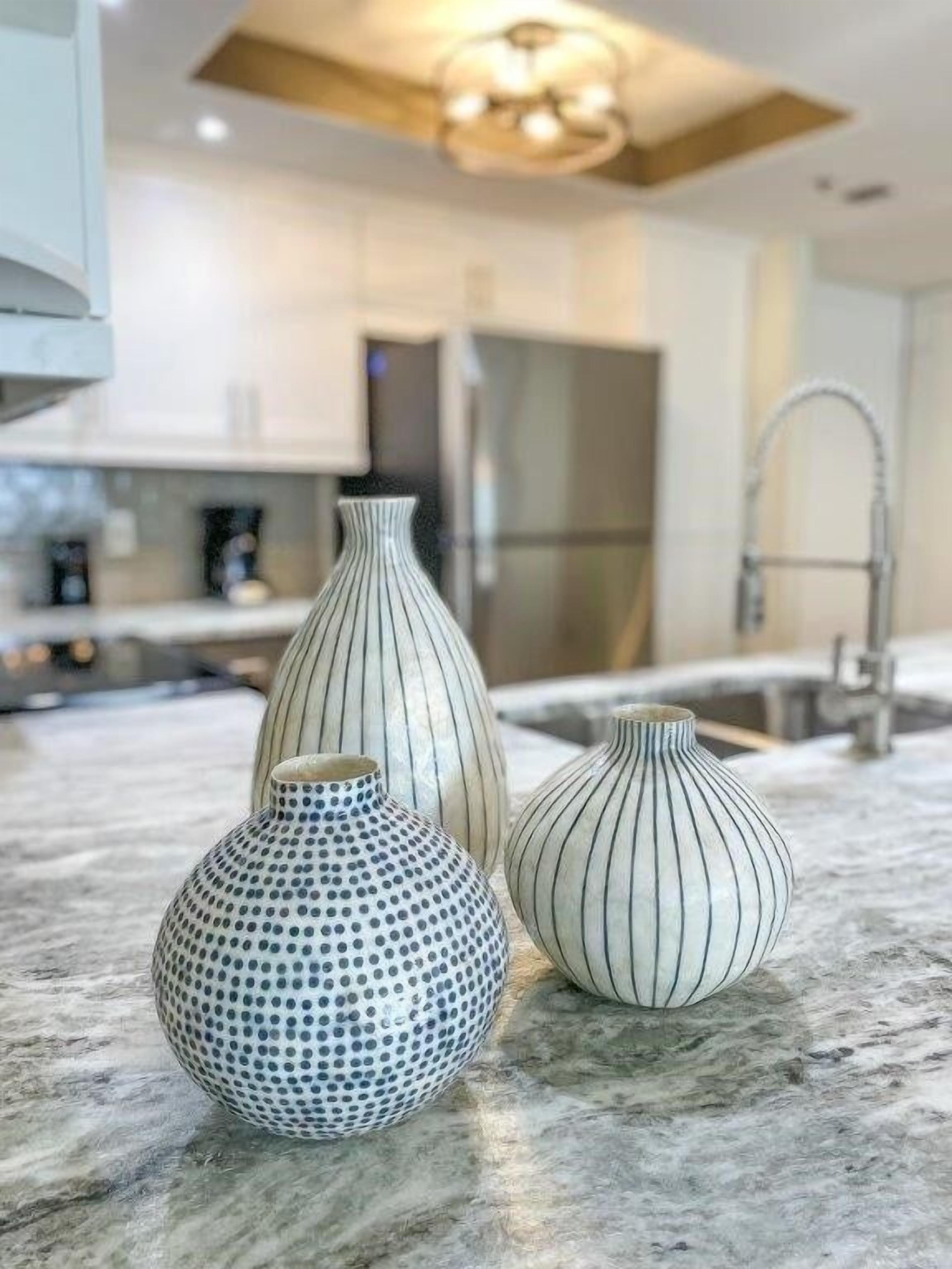 Three vases on a kitchen counter.