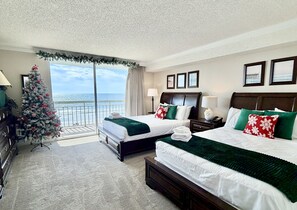 A hotel room with two beds, a Christmas tree, and a balcony with a view of the ocean. - Gorgeously remodeled 2 bedroom ocean front unit - 509 South Hampton 2 Condo (Myrtle Beach)