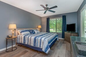Cozy retreat with a large bed, ceiling fan, and mounted TV.