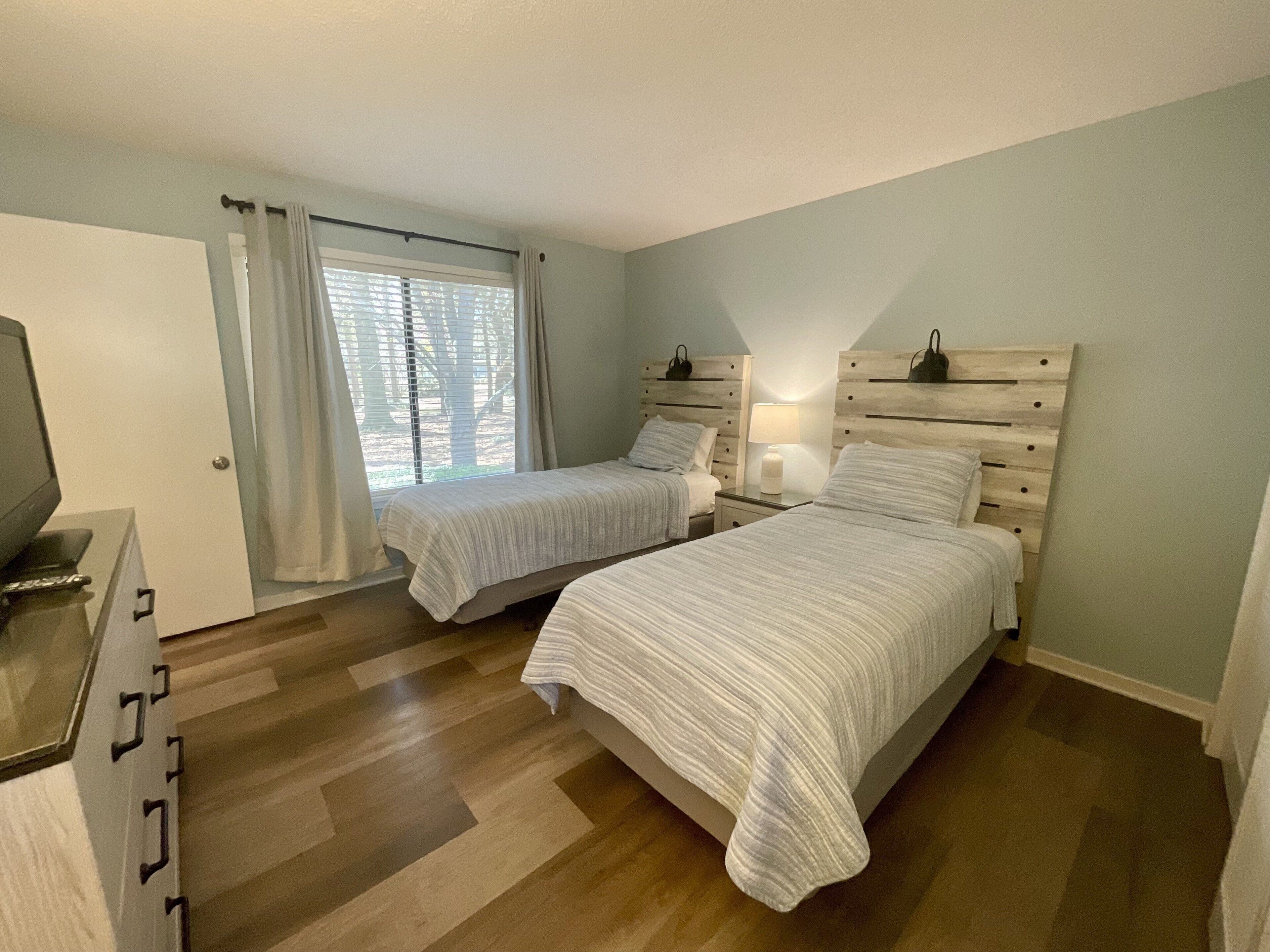 Une chambre avec deux lits, une télévision et une fenêtre avec des rideaux.