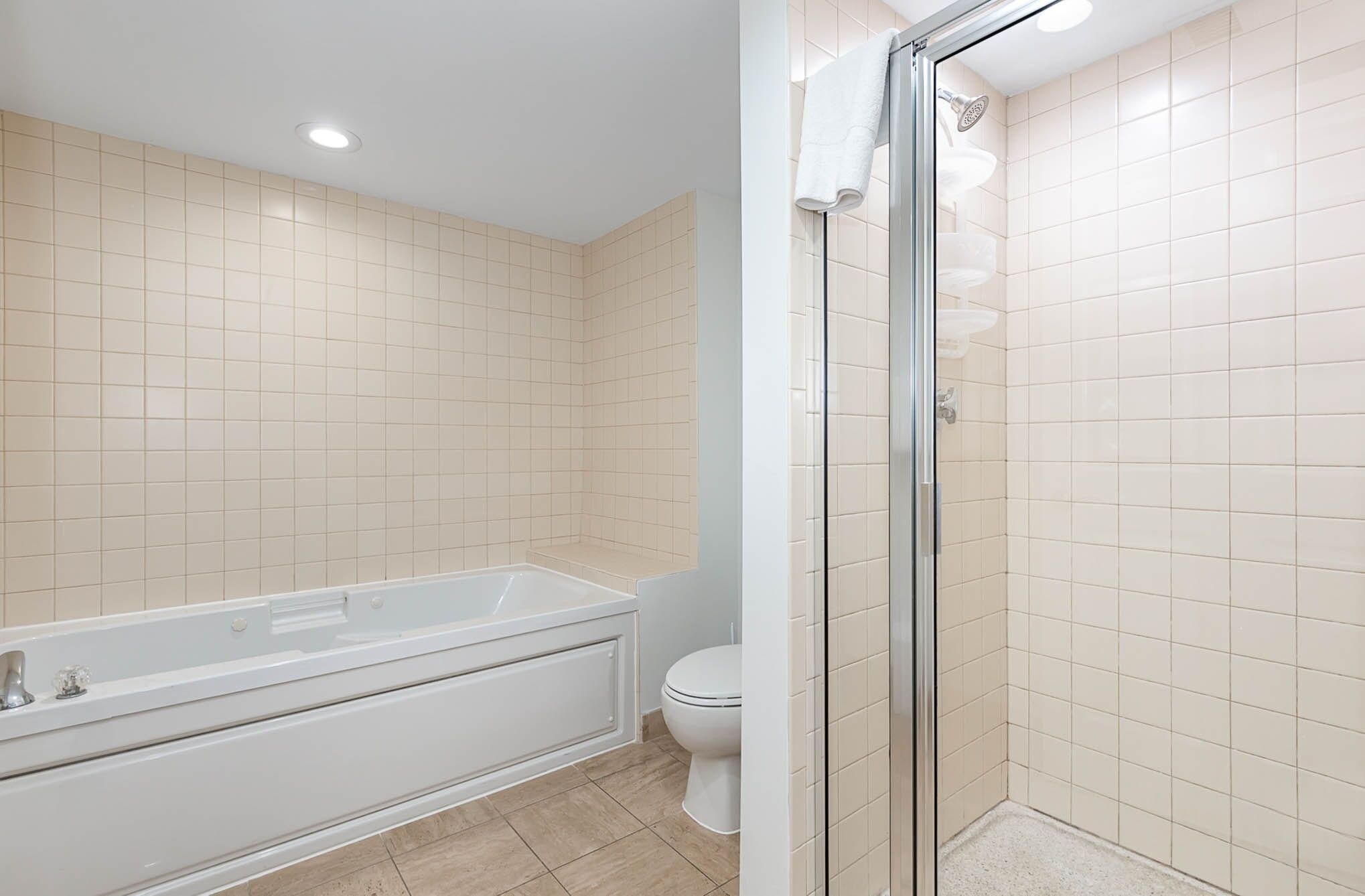 A bathroom with a bathtub, toilet, and glass shower enclosure.