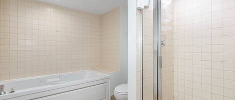 A bathroom with a bathtub, toilet, and glass shower enclosure.