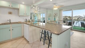A modern kitchen with a large island, light blue cabinets, and a view of a marina.