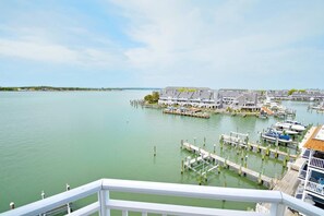 A marina with docked boats, a waterfront building complex, and a clear sky.