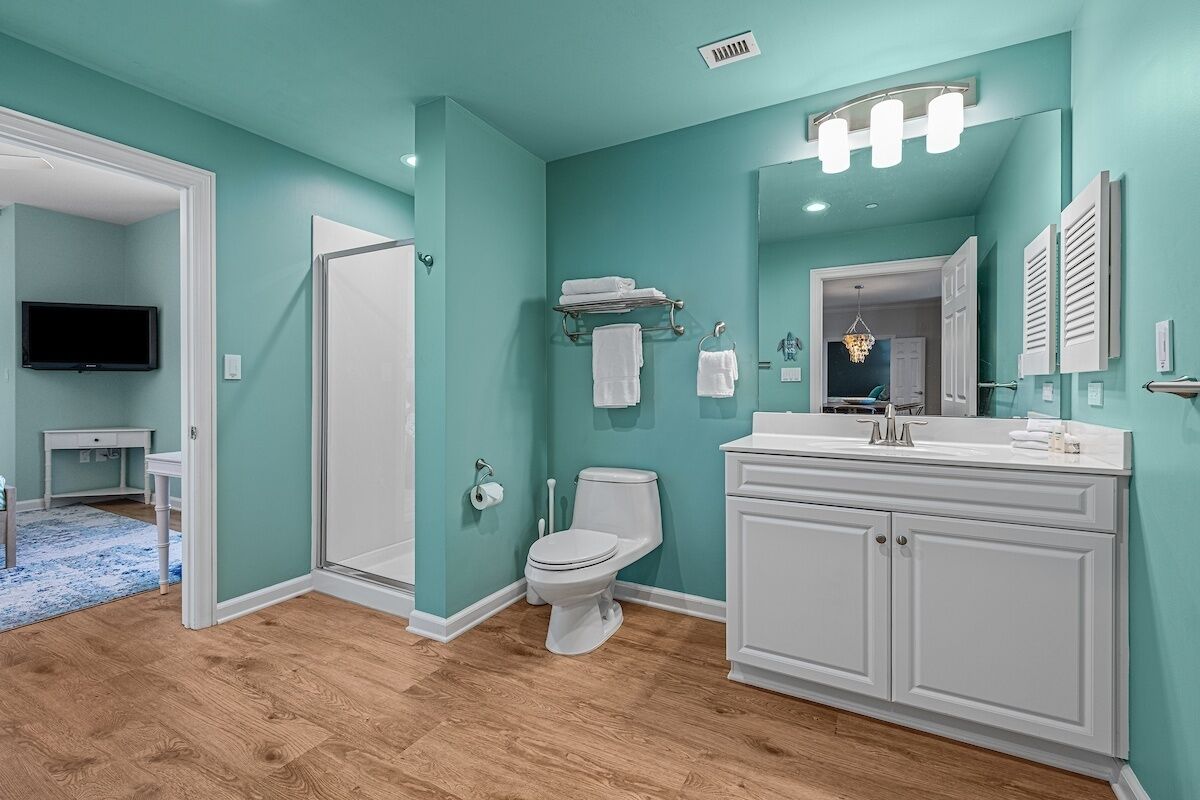 A bathroom with a white toilet, a vanity with a mirror, and a sink.