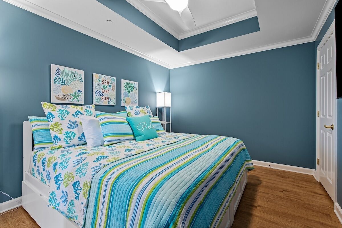A bedroom with a bed, blue walls, and a ceiling light.