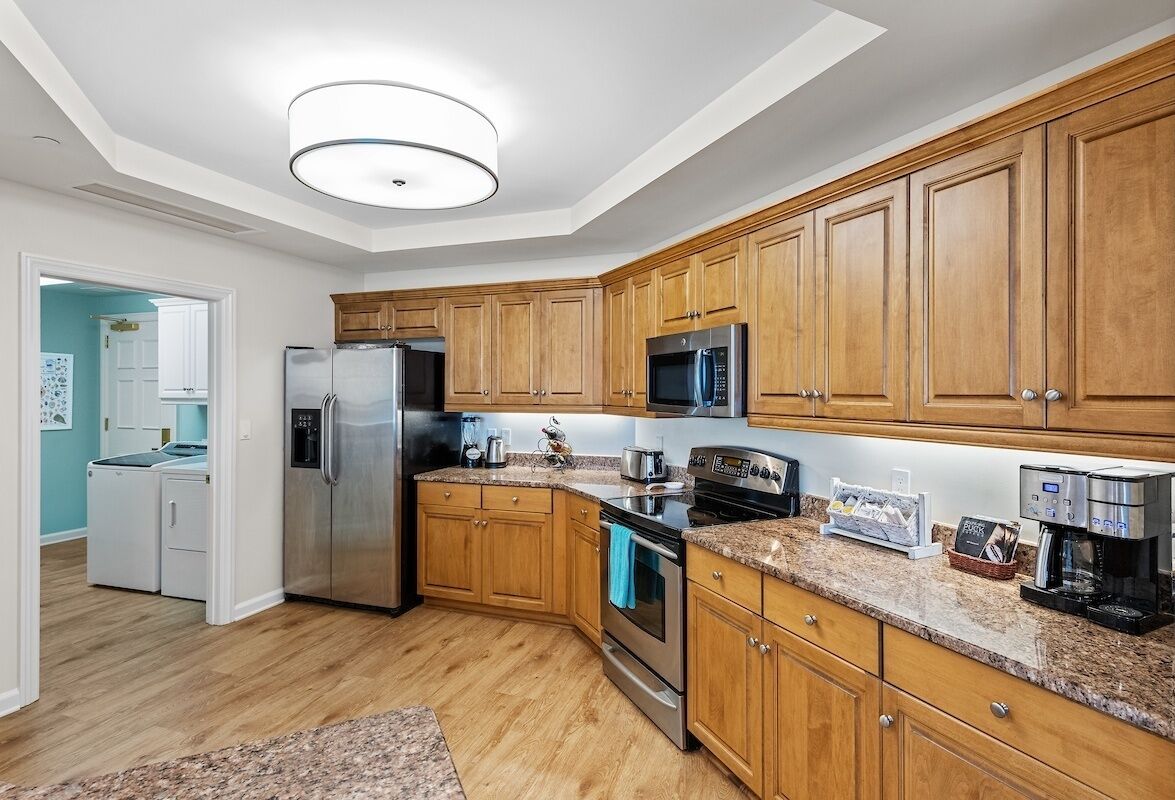 A modern kitchen with wooden cabinets, stainless steel appliances, and a granite countertop.