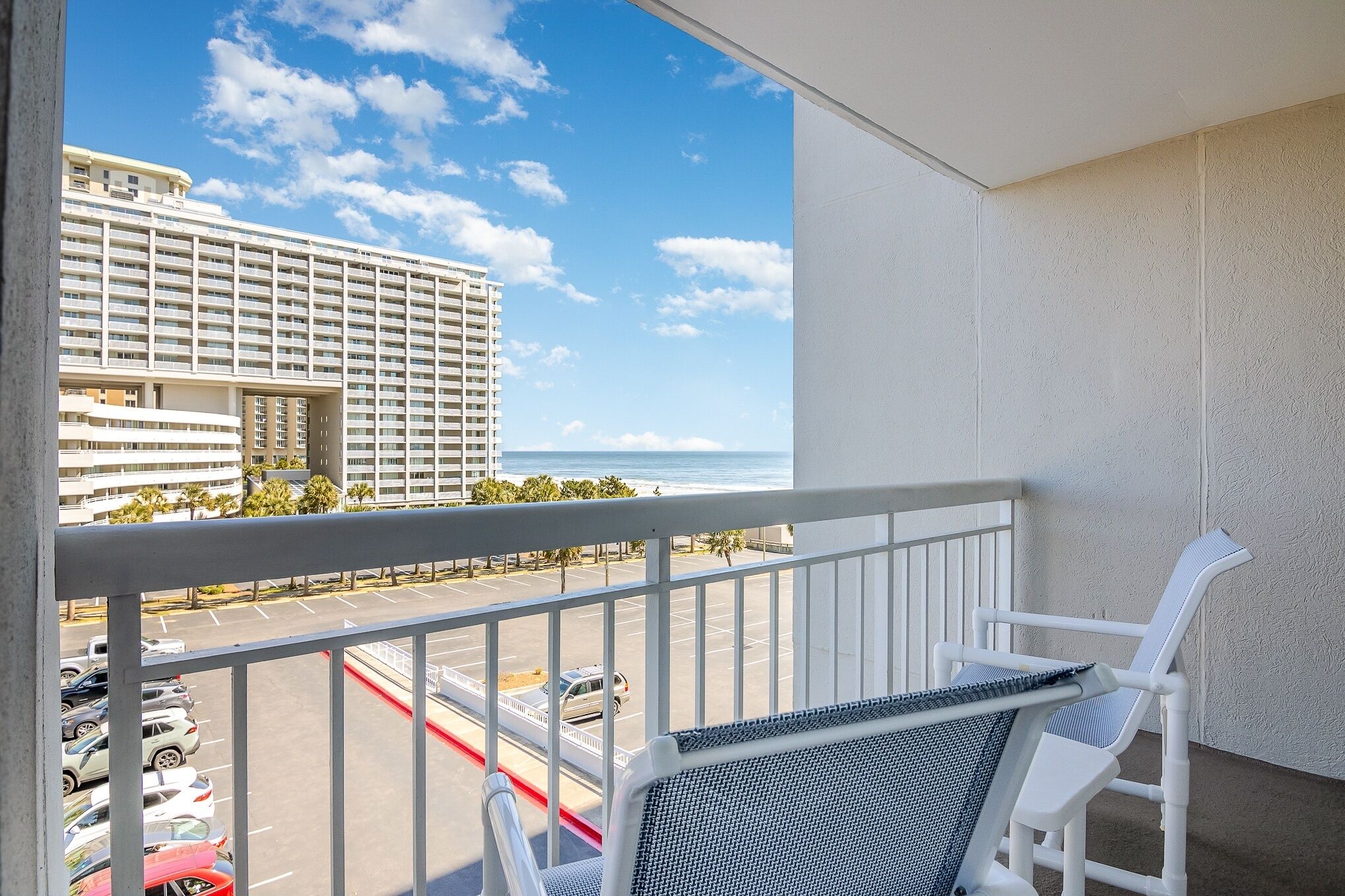 Ein Balkon mit Blick auf einen Parkplatz und ein Hotelgebäude.