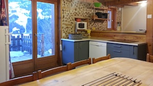 A wooden cabin kitchen with a stone wall, a microwave, and a sink. - Apartment at Chalet Le Cordé in Beaufort, Savoie. Dominant view (Beaufort)