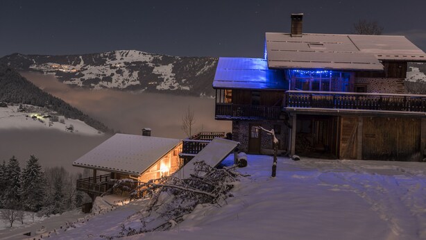 A snow-covered mountain lodge with a wooden exterior and a balcony with blue lighting. - Apartment at Chalet Le Cordé in Beaufort, Savoie. Dominant view (Beaufort)