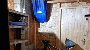 A room with a wooden door, a bicycle, and a blue container hanging from the ceiling. - Apartment at Chalet Le Cordé in Beaufort, Savoie. Dominant view (Beaufort)