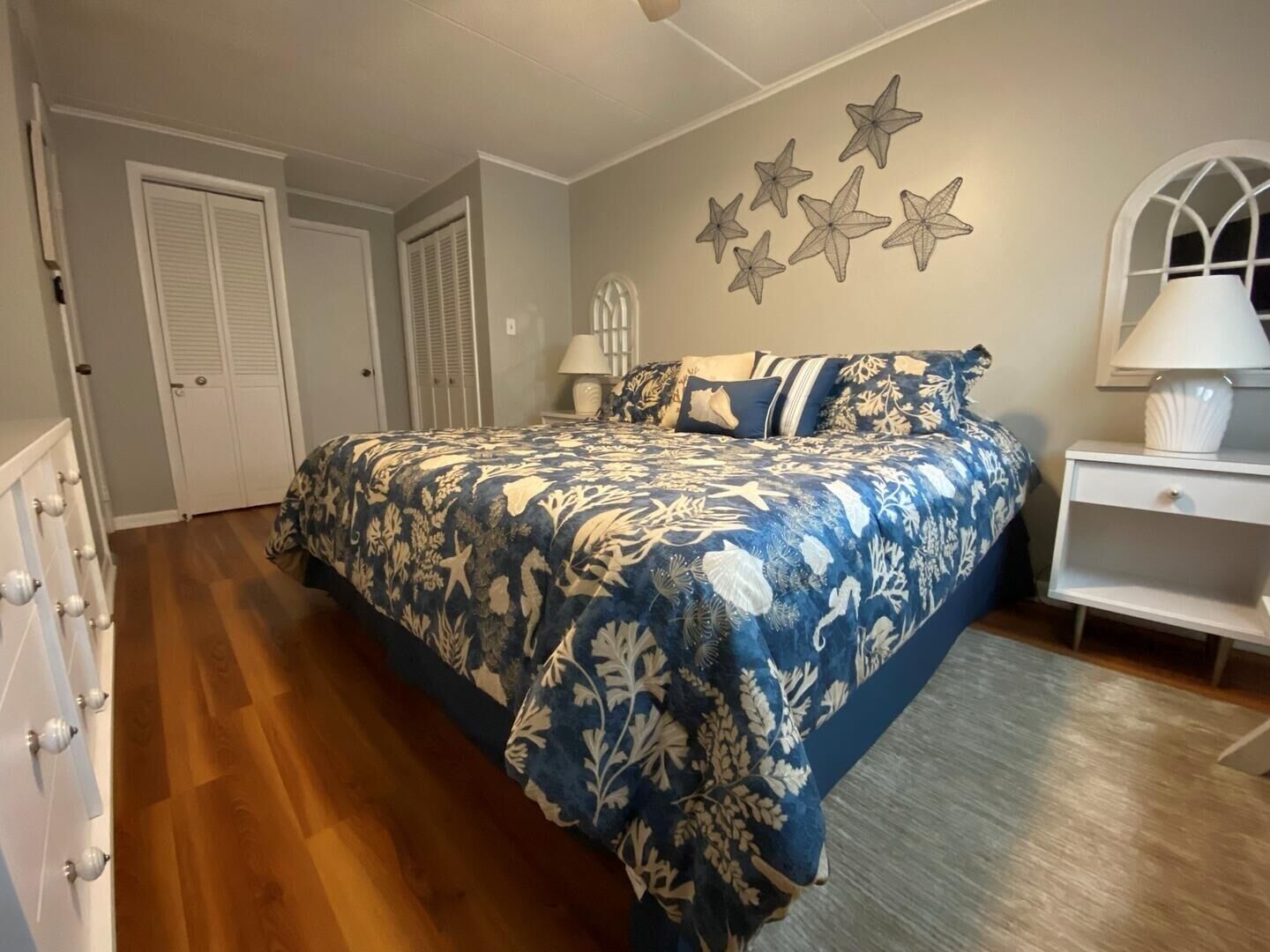 A bedroom with a bed, nightstands, a dresser, and a wall with star decorations.