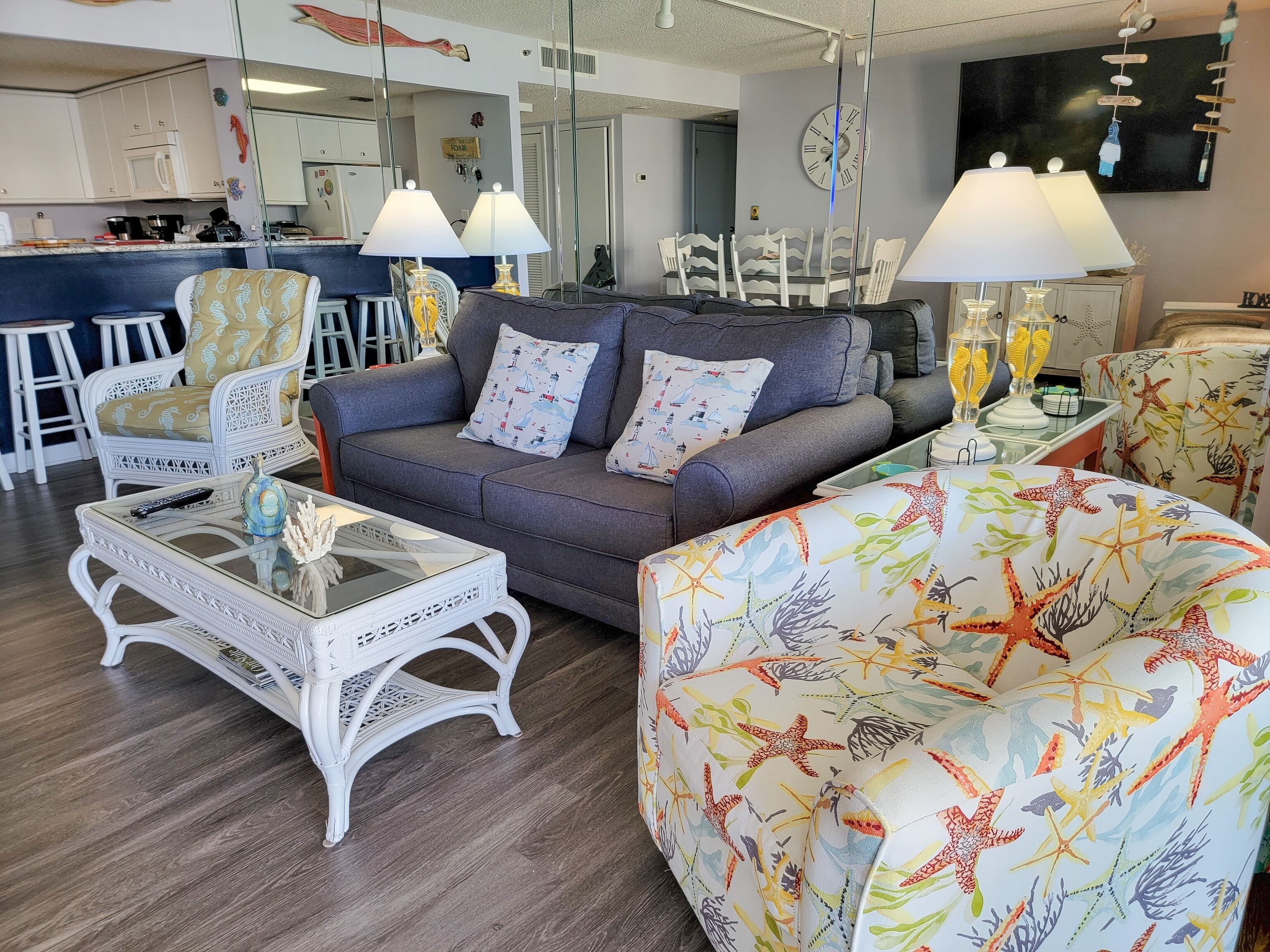 Een woonkamer met een bank, fauteuils, een salontafel en een eethoek met stoelen en een bar.