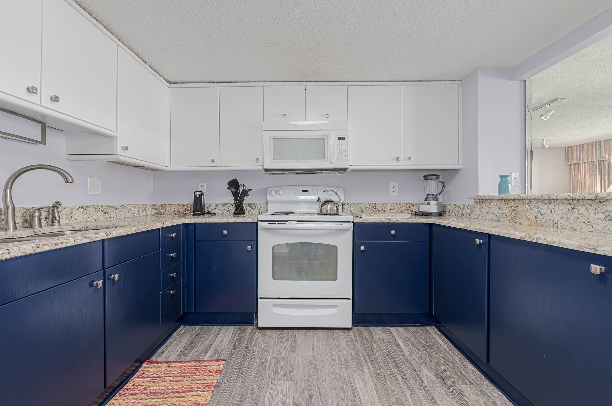 A modern kitchen with white cabinets, a built-in microwave, a stove, and a granite countertop.
