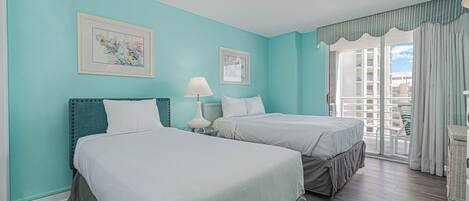 A hotel room with two beds, teal walls, and a balcony with curtains.