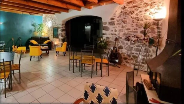 Un interior acogedor con pared de piedra, vigas de madera en el techo y sillas amarillas.