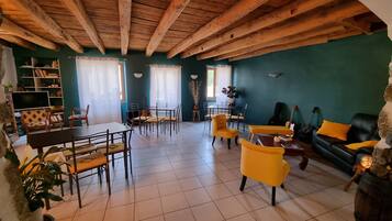 A spacious living room with wooden beams, a dining area, and a sofa.