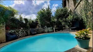 Una piscina rodeada de muros de piedra y follaje.