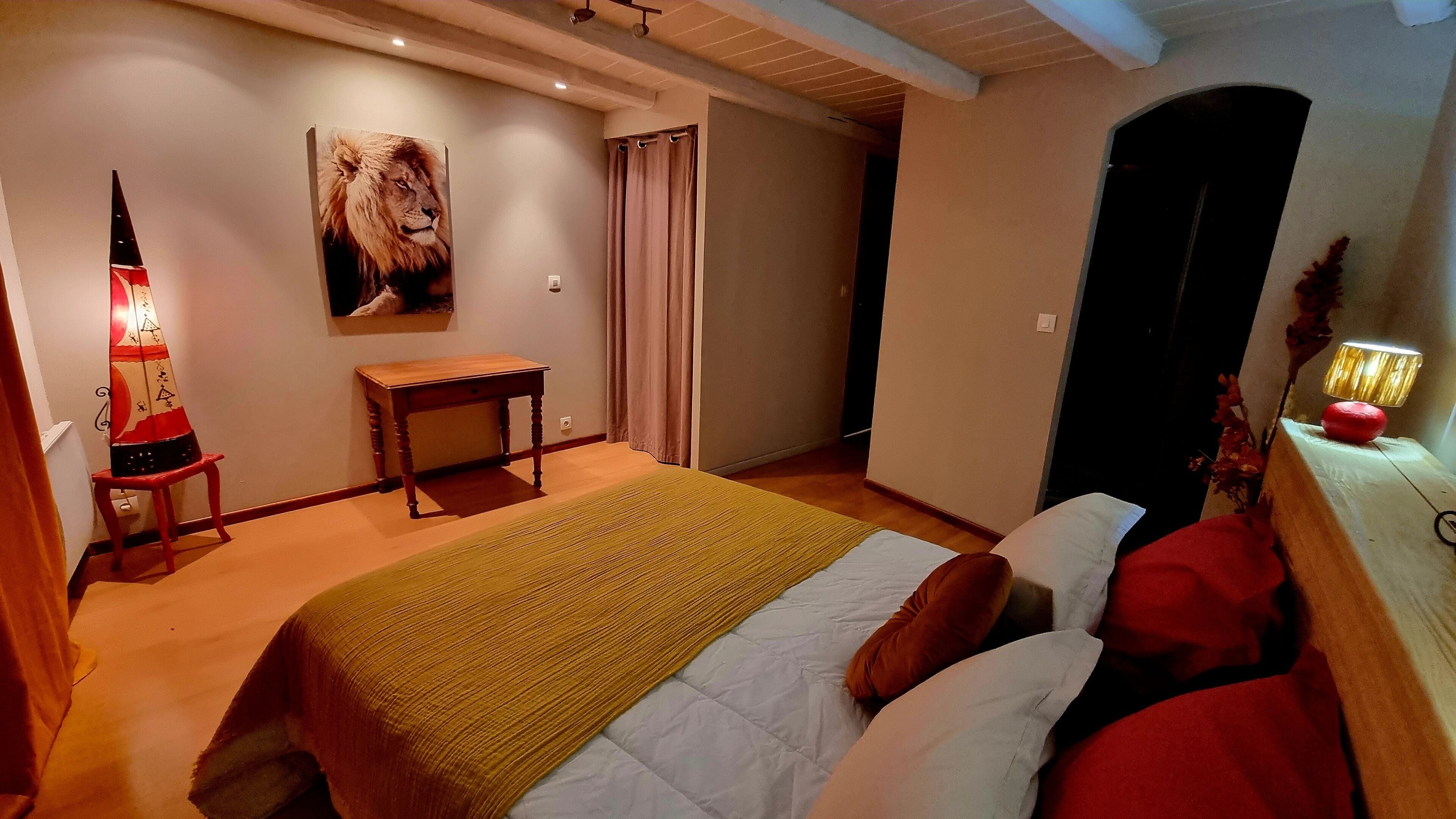 Une chambre à coucher avec un lit, une table de chevet, une lampe, un tableau et une porte.