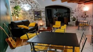 Un salón acogedor con un sofá negro, sillas amarillas, una mesa de comedor y una guitarra.